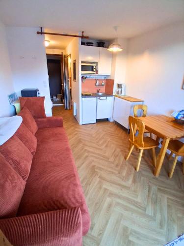 Studio SnowCarroz with a view for 4 people في Arâches-la-Frasse: غرفة معيشة مع أريكة حمراء وطاولة