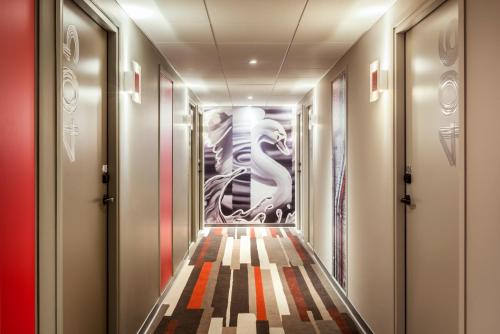 un couloir d'ascenseur avec une peinture sur le mur dans l'établissement ibis Saint Quentin en Yvelines - Vélodrome, à Montigny-le-Bretonneux