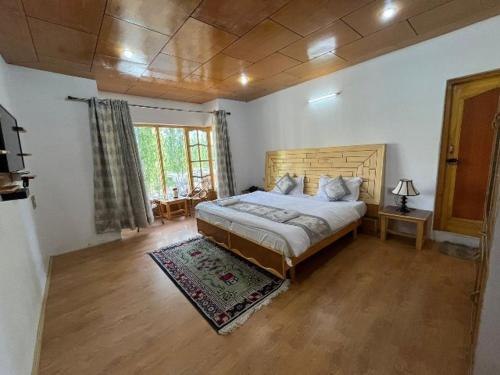 a bedroom with a large bed with a wooden headboard at Hotel Namgyal Villa in Nubra