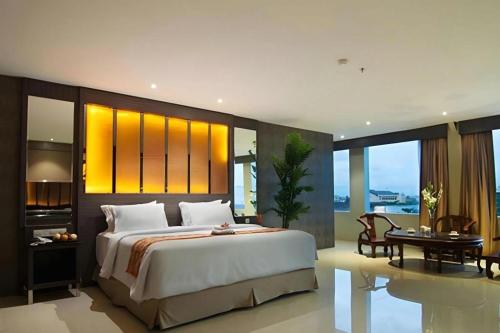 a bedroom with a large bed and a table and chairs at Aria Barito Hotel in Banjarmasin