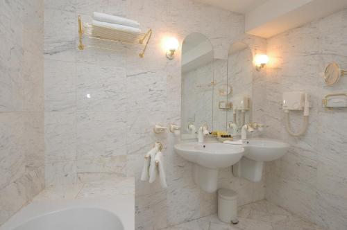 a bathroom with a sink, mirror, and bathtub at Hotel Dvorak Cesky Krumlov in Český Krumlov