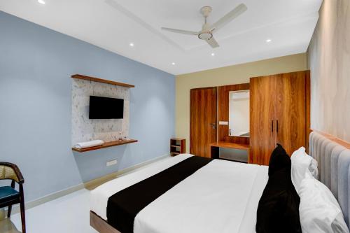 una camera da letto con un letto bianco e una tv di Hotel O Sri Aditya Utsav a Hakīmpet