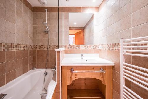 ein Badezimmer mit Waschbecken und Badewanne in der Unterkunft Le Chalet - C204 - Vue Montagne in Le Corbier