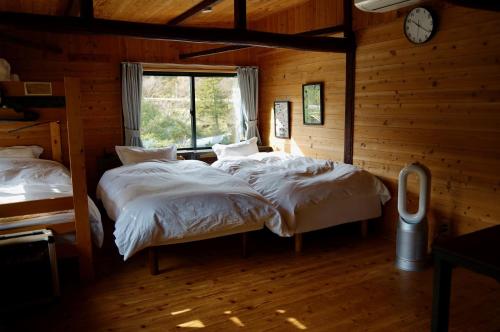 Sakura House サクラハウス 高知駅から車で20分-豊かな自然を味わう山の隠れ家 في كوتشي: سريرين في غرفة مع ساعة على الحائط