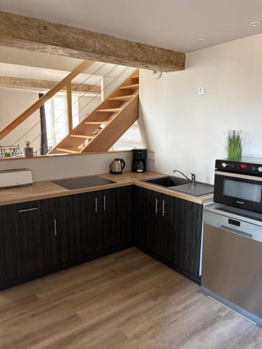 uma cozinha com armários de madeira e uma escada em Les Glaneuses gîte Entre Amis centre-bourg à 3 min du Puy duFou em Les Épesses