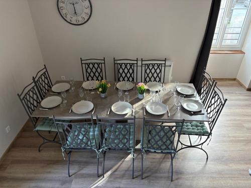 uma mesa de jantar com cadeiras e um relógio na parede em Les Glaneuses gîte Entre Amis centre-bourg à 3 min du Puy duFou em Les Épesses