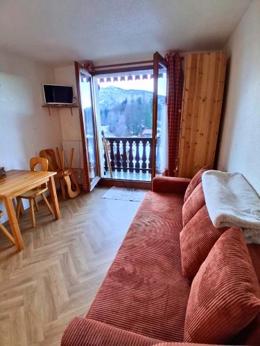 Studio SnowCarroz with a view for 4 people في Arâches-la-Frasse: غرفة معيشة مع أريكة وطاولة وشرفة