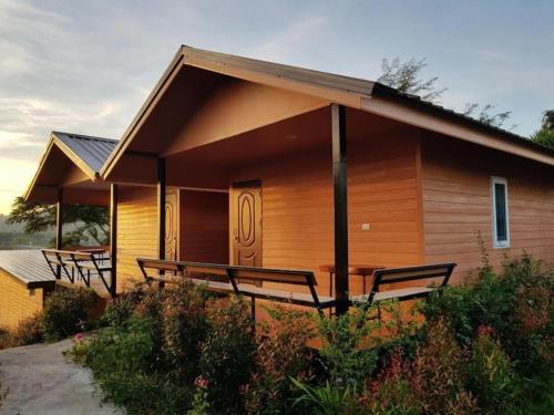 Jit Dee Home Khao Kho في كاو كو: كابينة خشبية أمامها مقاعد
