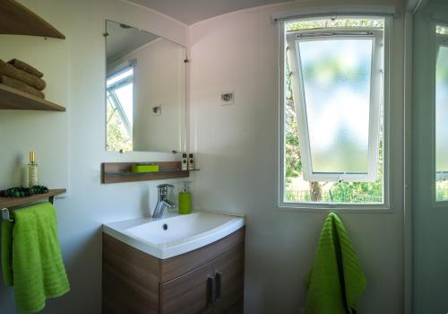 a bathroom with a sink and a window at Camping Officiel Siblu Le Lac des Rêves in Lattes