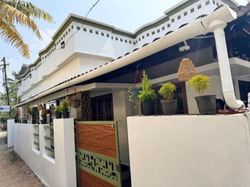 een wit gebouw met potplanten erop bij White coral beach home in Alleppey