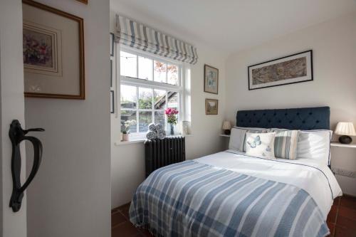 een slaapkamer met een bed met een blauw hoofdeinde en een raam bij The Cottage in Fernhurst