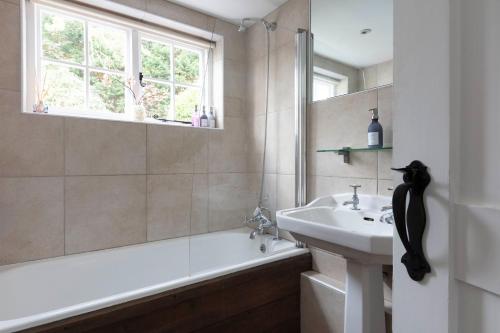 een badkamer met een bad, een wastafel en een bad tubermottermott bij The Cottage in Fernhurst
