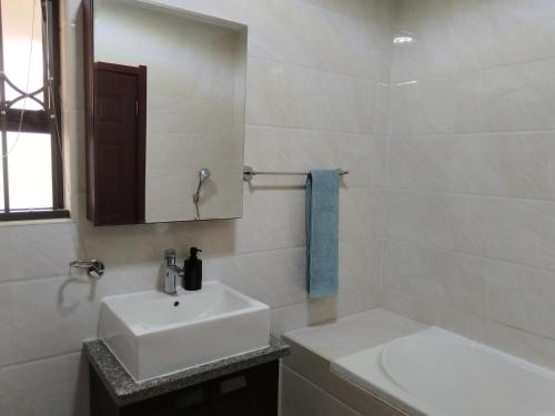 een witte badkamer met een wastafel en een spiegel bij Two Lilies in Vosburg