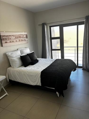 een slaapkamer met een bed met zwart-witte kussens bij Modern Getaway in Rand Rifles