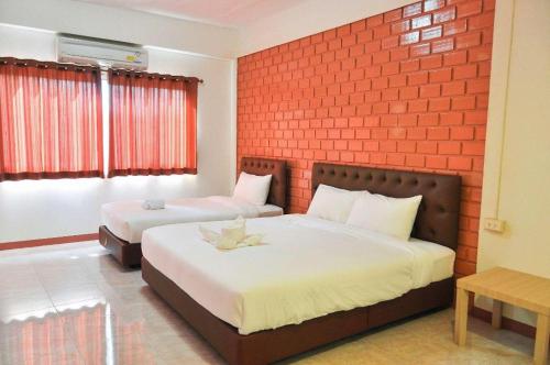 a bedroom with two beds and a red brick wall at Bussarakam Place Hotel in Ban Chamun (2)