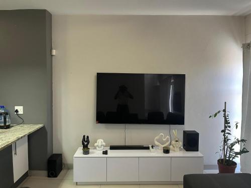 een woonkamer met een tv aan een witte muur bij Modern Getaway in Rand Rifles