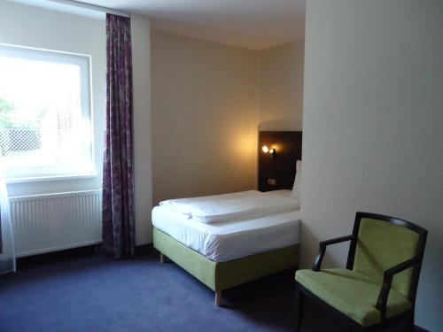 - une chambre avec un lit, une chaise et une fenêtre dans l'établissement MSR Hotel Hannover, à Hanovre