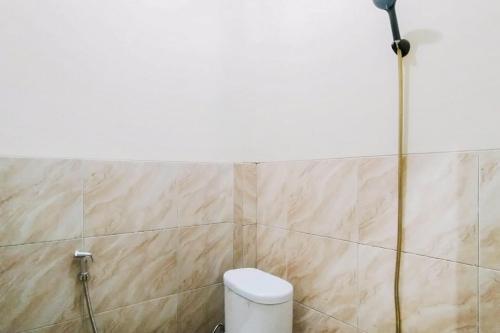 a bathroom with a toilet and a white wall at Nirina Homestay Pringsewu Mitra RedDoorz in Margakaya