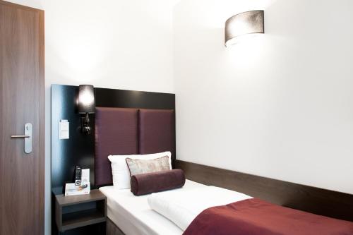 a hotel room with a bed and a lamp at Fair Hotel Europaallee in Frankfurt