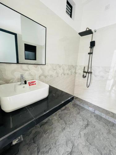 a white bathroom with a sink and a mirror at Dondra OceanLight Villa in Gandara East