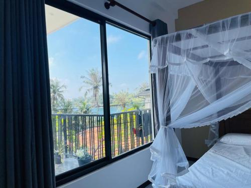 a bedroom with a window with a view of a balcony at Dondra OceanLight Villa in Gandara East