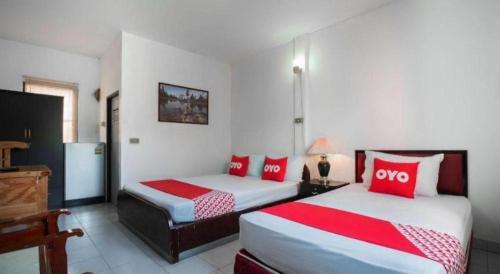two beds in a room with red and white pillows at OYO 654 Samanmit Inn Hotel in Ban Tao Than