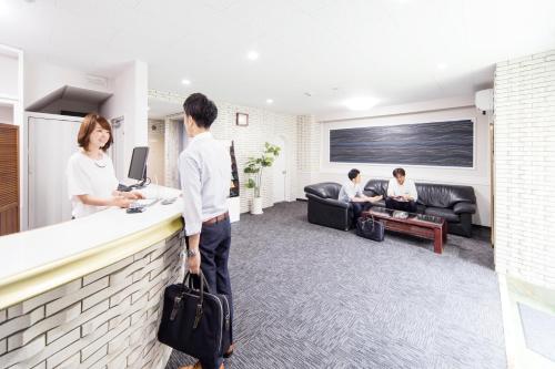 a group of people sitting at a counter in a room at Best Hotel in Tokyo