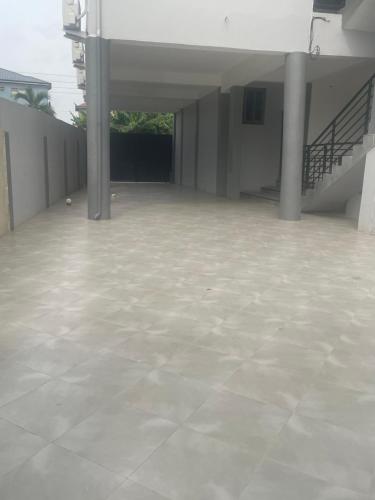 a large empty room with a white floor and stairs at Nick Jaaks Courtyard-Single Room in Accra