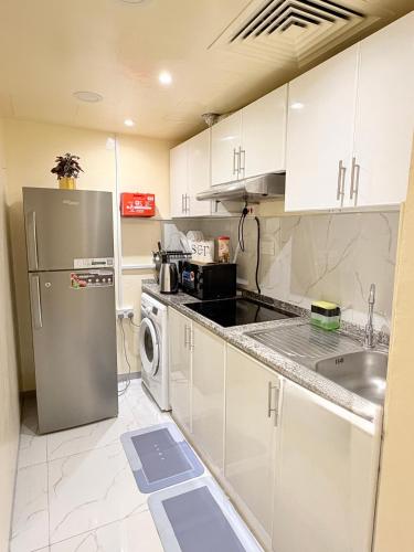 a kitchen with white cabinets and a stainless steel refrigerator at PrimeLuxe Stay by Lavishhub in Abu Dhabi