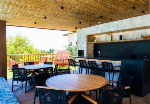 un patio avec tables et chaises et un bar dans l'établissement Lanai Imbassai, à Mata de São João