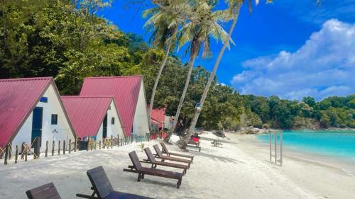 a group of chairs on a beach next to a building at DEWATI ROOMSTAY B&B in Lang Tengah