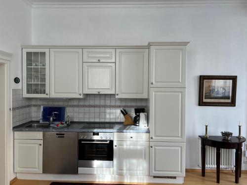 a kitchen with white cabinets and stainless steel appliances at Schöne Ferienwohnung in Seebad Bansin 200m vom Strand (Heringsdorf, Kaiserbäder, Usedom) in Bansin