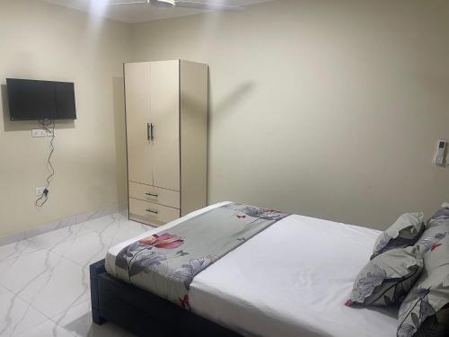 a bedroom with a bed and a cabinet and a tv at Nick Jaaks Courtyard-Single Room in Accra
