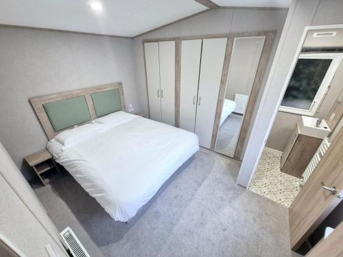 ein kleines Schlafzimmer mit einem weißen Bett und einem Spiegel in der Unterkunft Birchington Vale Arizona in Westgate-on-Sea