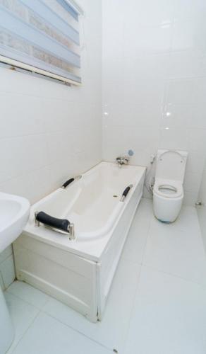 a white bathroom with a tub and a toilet at Pkeys in Lekki