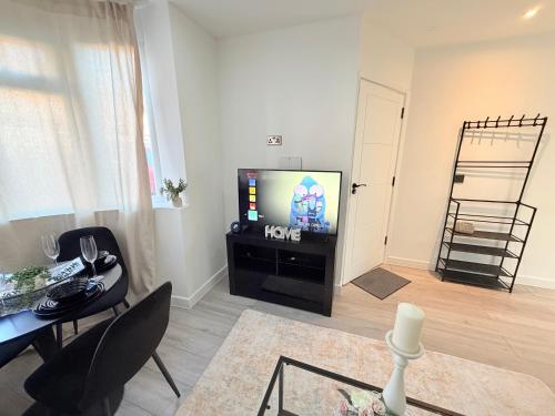 un soggiorno con TV e tavolo e una sala da pranzo di Cozy Escape Garden Flat a Birmingham