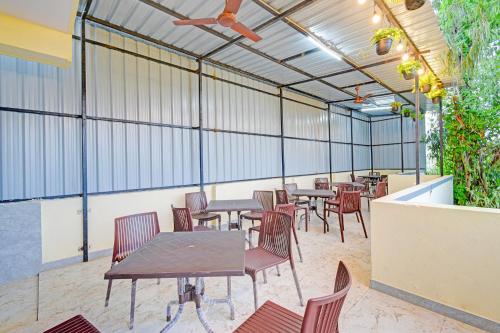 una cafetería con mesas, sillas y plantas en FabHotel Legacy, en Hyderabad