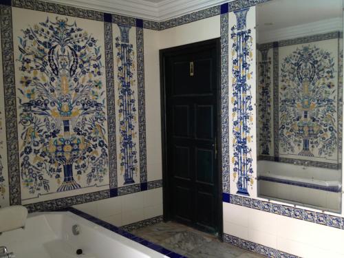 迈来亚Hotel Djerba Orient的浴室设有黑色的门,铺有蓝色和白色的瓷砖。