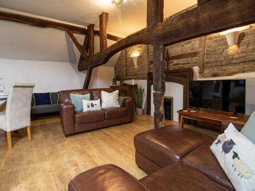 a living room with leather furniture and a flat screen tv at Blists Hill Cottage Near Ironbridge Victorian Museum in Telford