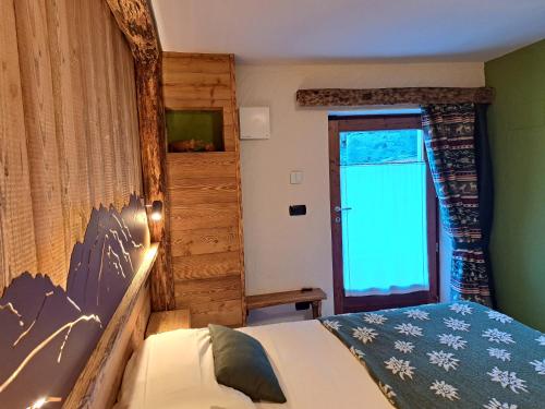 a bedroom with a bed and a large window at L'Abreny in Brusson