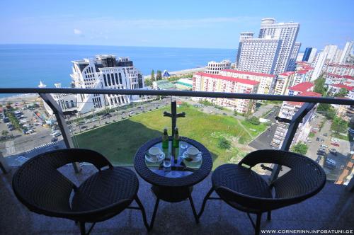 a balcony with three chairs and a view of a city at Hotel Corner Inn in Batumi