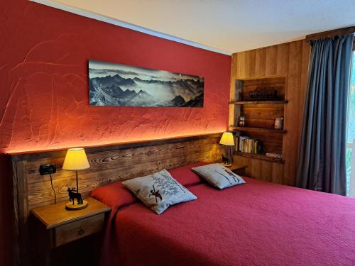 a red bedroom with a bed with two pillows at L'Abreny in Brusson