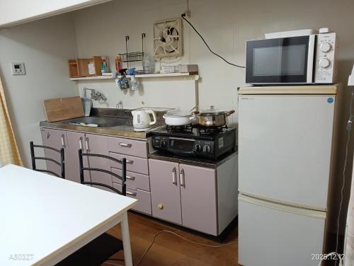 eine Küche mit einem Herd, einer Mikrowelle und einem Kühlschrank in der Unterkunft marusan houseマルさんの家 in Osaka