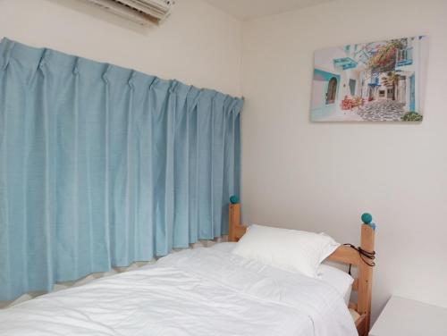 ein Schlafzimmer mit einem Bett und einem blauen Vorhang in der Unterkunft marusan houseマルさんの家 in Osaka
