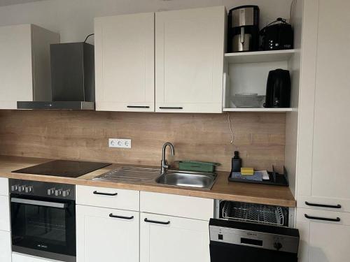 een keuken met witte kasten en een spoelbak bij Haus Monika in Juist