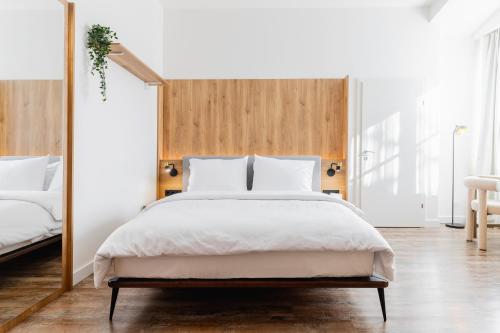 - une chambre avec un lit blanc et une tête de lit en bois dans l'établissement FortyPlusOne Apartments Vienna, à Vienne