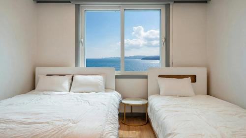 zwei Betten in einem Zimmer mit großem Fenster in der Unterkunft Donghae Hill Stay Pension in Donghae