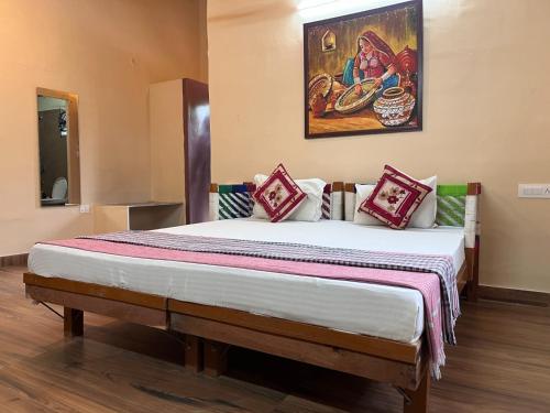 een slaapkamer met een groot bed met een schilderij aan de muur bij Gramya Resort in Alwar