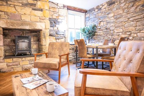 a stone room with a table and chairs and a fireplace at Northern Hideaways St Cuthberts, Seahouses in Seahouses