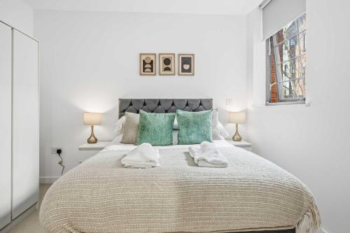 a white bedroom with a large bed with green pillows at Spacious & Modern 2BED Apartment in Birmingham in Birmingham